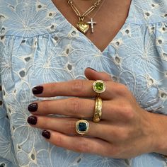 a woman wearing three different rings on her fingers and one with a cross in the middle