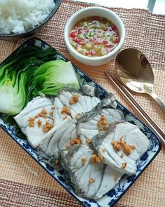 some food is on a plate with chopsticks next to it and a bowl of rice