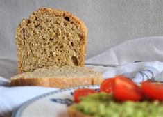 a loaf of bread sitting on top of a blue and white plate next to tomatoes