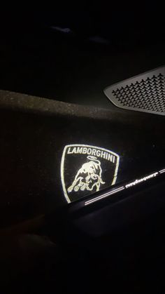 the lamb logo is shown on the side of a car in the dark with its hood up