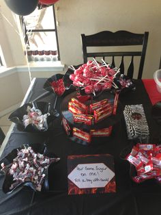 candy and candies are on display in front of a black table with red decorations