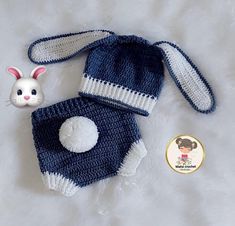 a crocheted bunny hat and diaper cover on a white blanket next to a toy rabbit