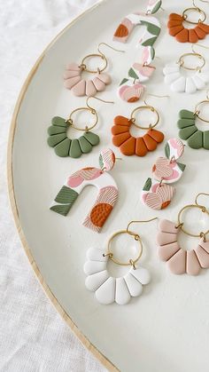 a white plate topped with lots of different colored earrings