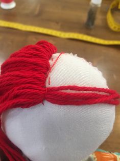 a close up of a red and white ball of yarn next to a measuring tape