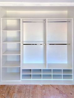 an empty closet with white shelves and drawers on the wall, in front of a wooden floor