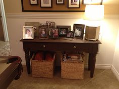 a table with two baskets under it and pictures on the wall