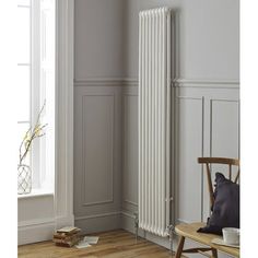 a white radiator in the corner of a room next to a wooden chair