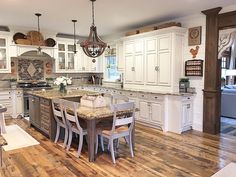 a large kitchen with white cabinets and wooden flooring, an island table surrounded by four chairs