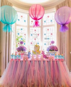 the table is decorated with pink, blue and purple tissue pom - poms