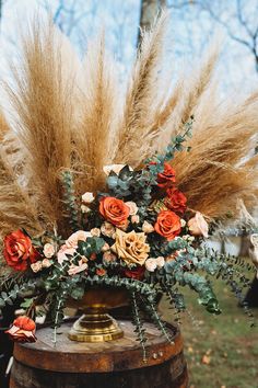 an arrangement of flowers and plants on top of a barrel