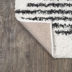 an area rug that has been placed on top of a wooden floor with grey and white stripes