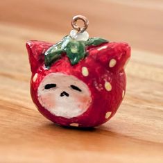 a red ceramic strawberry with a white face and green leaves on it's head