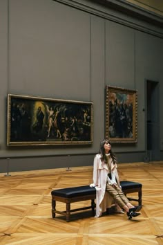 a woman sitting on a bench in an art museum