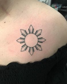 a woman's shoulder with a sun tattoo on it