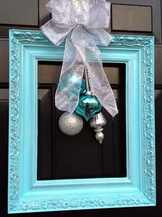 a blue frame with ornaments hanging from it's side and a bow on the front door