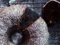 a chocolate bundt cake with powdered sugar on top sitting on a cooling rack