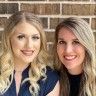 two women standing next to each other in front of a brick wall and smiling at the camera