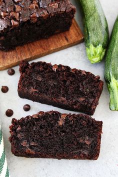 two slices of chocolate zucchini bread on a cutting board next to cucumbers