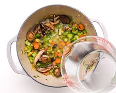 a pot filled with vegetables and mushrooms next to a measuring cup