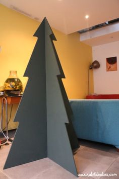 a small christmas tree sitting in the middle of a living room next to a couch