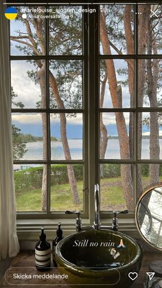 a bathroom sink sitting under a window next to a forest filled with lots of trees