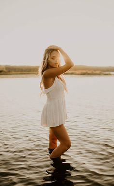 a woman standing in the water with her arms behind her head