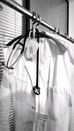 black and white photograph of clothes hanging on a rack in front of a window with blinds