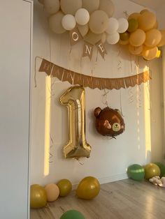 balloons and streamers are hanging from the ceiling in front of a one - year birthday banner