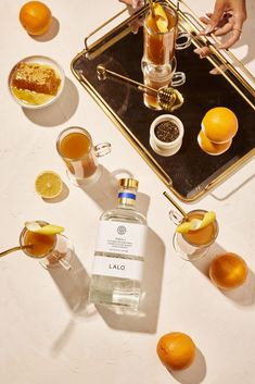 a table topped with oranges and glasses filled with liquid next to an empty bottle