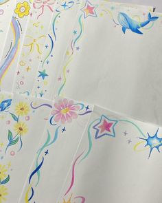 four sheets of white paper with colorful designs and stars on the side, all lined up together