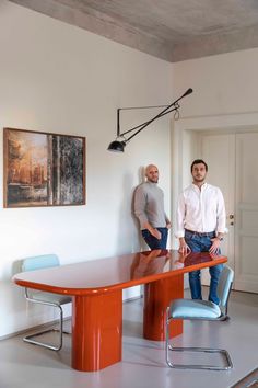 two men standing next to a table in a room