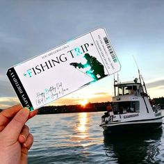 a person holding up a ticket to a fishing trip on the water at sunset with a boat in the background