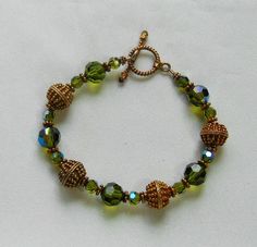 Wire strung bracelet with etched gold tone metal beads & aurora borealis green faceted crystal glass beads.  Length:  8".  Toggle clasp.  Beads are vintage. Aurora Borealis Green, Strung Bracelet, String Bracelet, Faceted Crystal, Vintage Bracelets, Toggle Clasp, Green Bead, Bracelets And Charms, Metal Beads