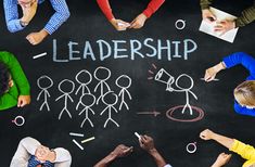 a group of people standing in front of a blackboard with the words leadership written on it