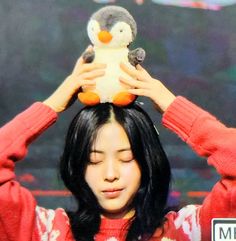 a woman holding a stuffed penguin on top of her head