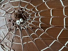 the chocolate cake is decorated with spider webs and googly eyes on it's sides