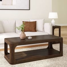 a living room with a white couch and wooden coffee table in front of a painting on the wall