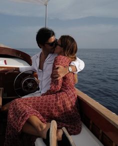 a man and woman kissing on the back of a boat