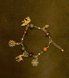 "A bracelet specially designed with the season of Yule in mind. Crystals: Garnet & Bloodstone. Charms: Bran, Pine Tree, Stag, Snowflake, Pine Cone. Other beads: Firepolish bead in gold. Please note Bloodstone naturally varies in color. Bracelet is 9in total but can be closed starting at 7 3/4in. Crystals, animals, colors and symbols correspondences researched and carefully selected using Edain McCoy's \"Sabbats. A witch's approach to living the Old Ways\" and Llewellyn's Sabbat Essentials Collection. Stones, beads and charms cleansed with Sabbat appropriate incense.  Jewelry items are placed in a reusable muslin bag with beautifully scented dried lavender from my own garden, and lots of good vibes. Fill your muslin bag with additional herbs to toss in your bathtub for a beautifully scented Metal Crystal Bracelet For Gift, Metal Beaded Charm Bracelet Gift, Metal Crystal Bracelet With Charms For Gift, Metal Crystal Bracelet With Charms As Gift, Handmade Metal Crystal Bracelet As A Gift, Crystal Metal Bracelet With Lobster Clasp As Gift, Multicolor Christmas Bracelet Jewelry, Handmade Christmas Jewelry Bracelets, Metal Crystal Bracelet With Lobster Clasp As Gift