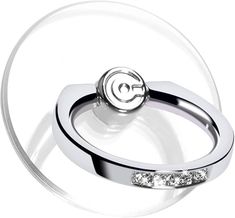 two silver rings with diamonds on them sitting in front of a circular object that looks like an acrobatic ring