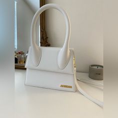 a white handbag sitting on top of a counter next to a phone and mirror