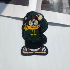 a teddy bear patch on the side of a white refrigerator freezer next to an open window