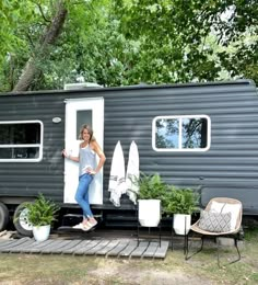 a woman standing in the doorway of a mobile home with potted plants and towels