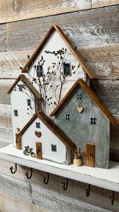 two white houses are sitting on a shelf with hooks in the shape of key holders