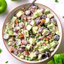 a bowl filled with cucumber salad next to green apples and lettuce