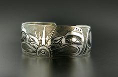 "This unisex Northwest Coast Native cuff has been hand-engraved. This bold bracelet measures 1\" wide by 6\" long, which will fit a wrist between 6 1/4\"-6 1/2\" in circumference. Custom lengths can be created on request by designer Kelvin Thompson. After this piece was hand-engraved using steel gravers and chisels, it was chemically oxidized to provide it with an antiqued look. This oxidization process really helps the design pop. This bracelet tells the \"Raven Steals the Light\" myth: \"At th Symbolic Stamped Cuff Bracelet, Symbolic Engraved Cuff Bangle Bracelet, Symbolic Etched Cuff Bracelet, Unique Engraved Cuff Bracelets, Symbolic Etched Cuff Bracelet Bangle, Symbolic Etched Bangle Cuff Bracelet, Wide Band Engraved Bangle Gift, Engraved Wide Band Bangle As Gift, Symbolic Engraved Ceremonial Cuff Bracelet