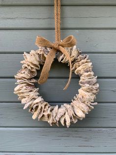 a wreath hanging on the side of a building with a burlock tied around it