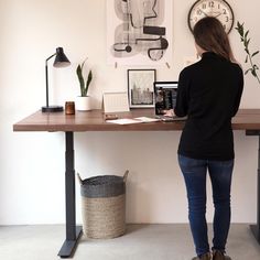 a woman standing at a desk in front of a clock