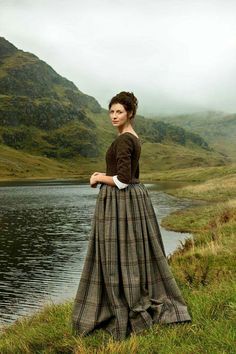 a woman in a long dress standing by the water