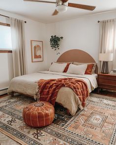 a bedroom with a bed, rugs and ceiling fan in the middle of it